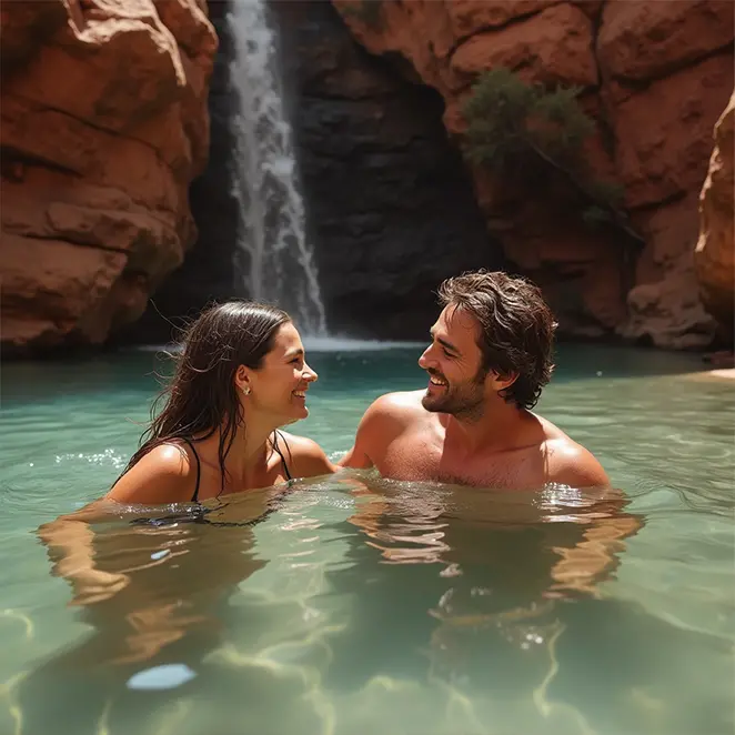 Un couple de jeunes mariés nageant et riant dans un bassin naturel aux eaux cristallines, dans la région du Kimberley, en Australie.