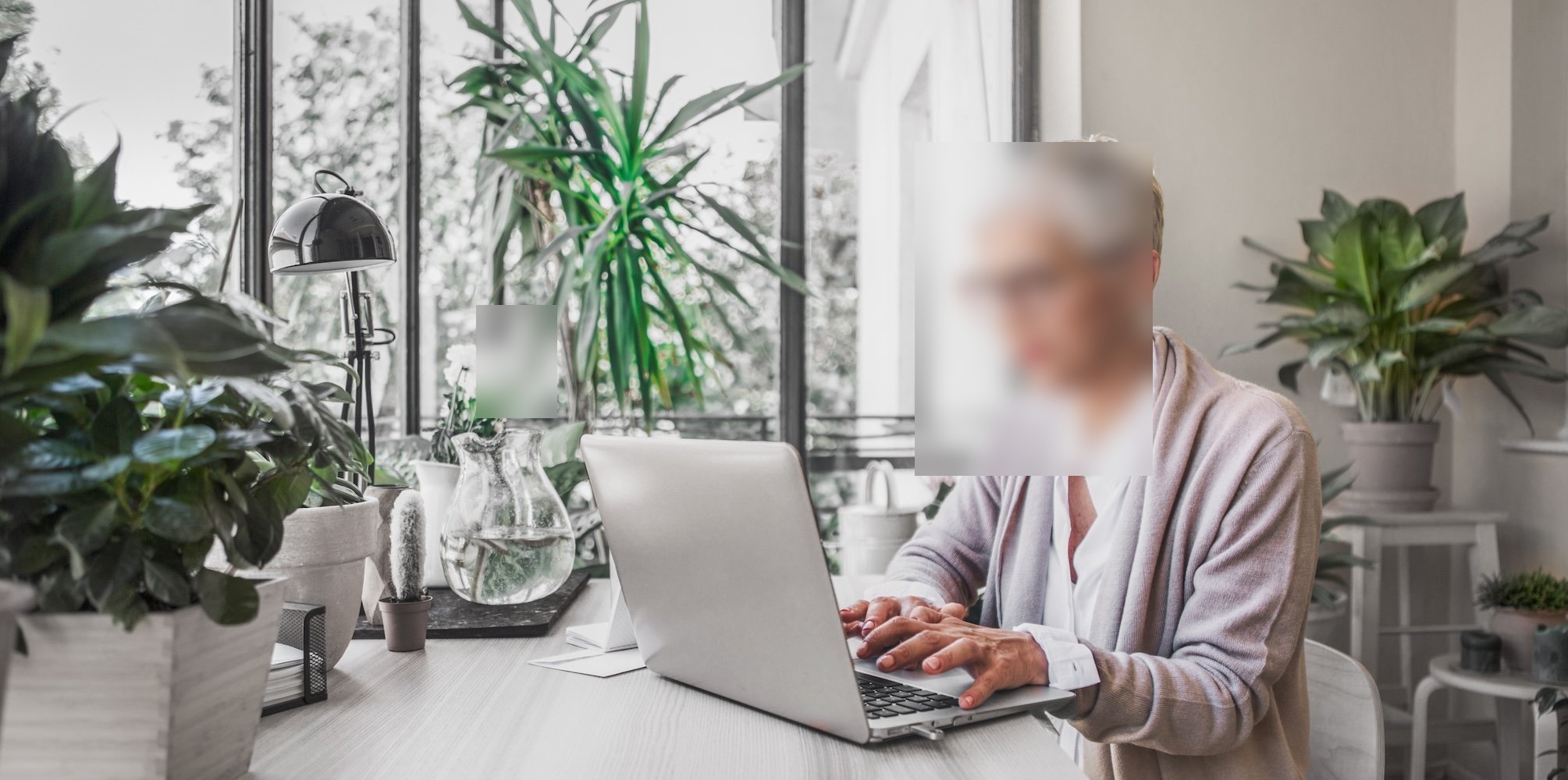 older woman with short hair typing on laptop at a desk