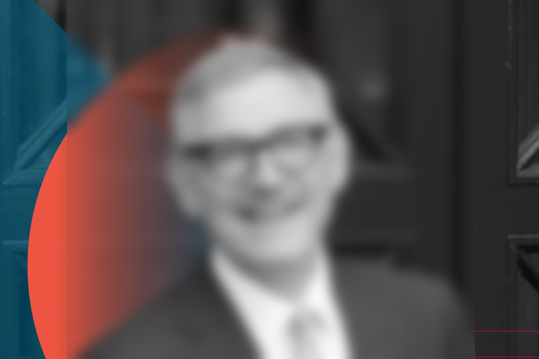 a black and white portrait of a smiling person with short hair, wearing glasses, a dark suit, and a light polka-dot tie, standing in front of dark double doors with a blue and red geometric overlay.