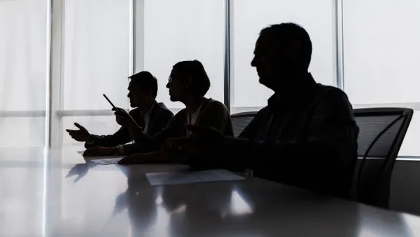 silhouette of several business people at a conference room table.