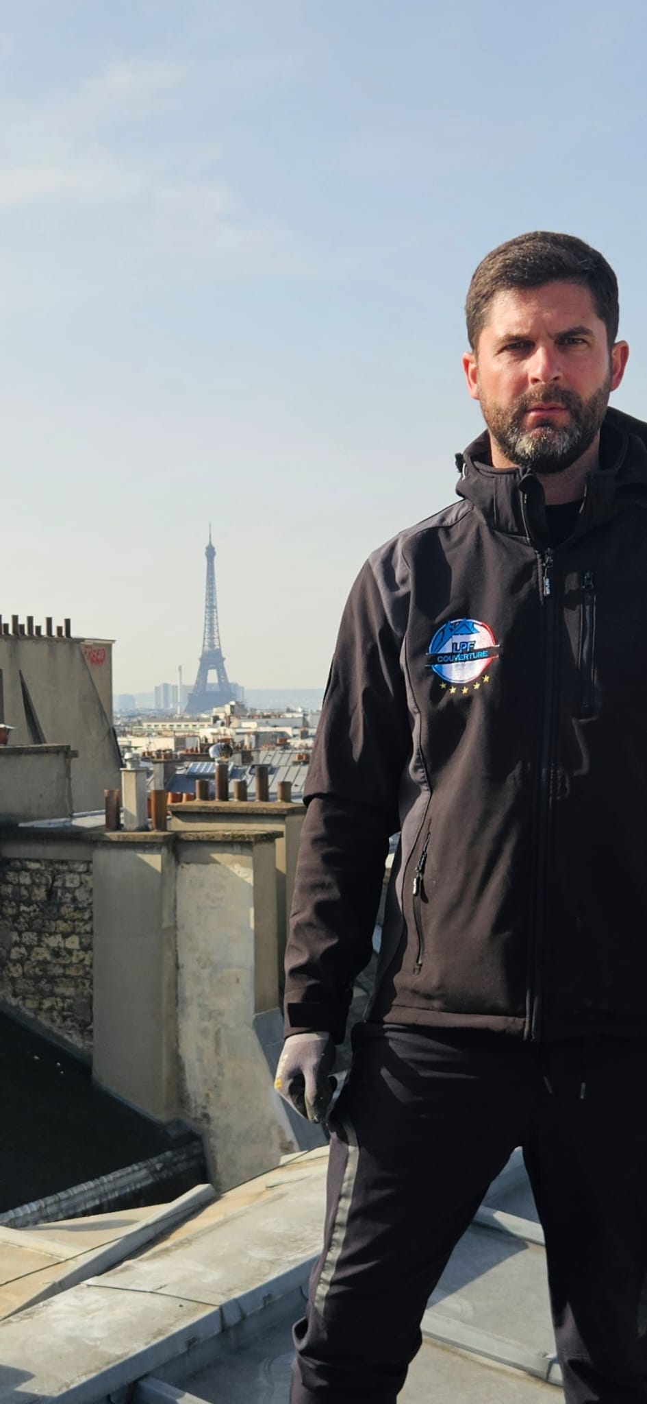 Le dirigeant de LPF Couverture sur un toit parisien avec la Tour Eiffel en arrière-plan