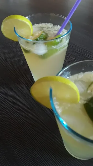 2 glasses filled with Mojito Cocktail on a dark table.